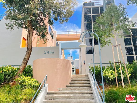 Front view of a modern multi-story building with large windows and a staircase leading to the entrance.