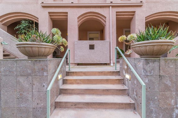 Front view of a building entrance with stairs and large planters.