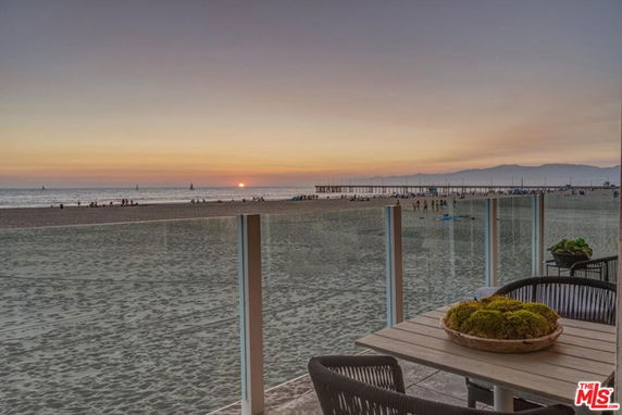 Panoramic view of the beach and ocean at sunset from a balcony.