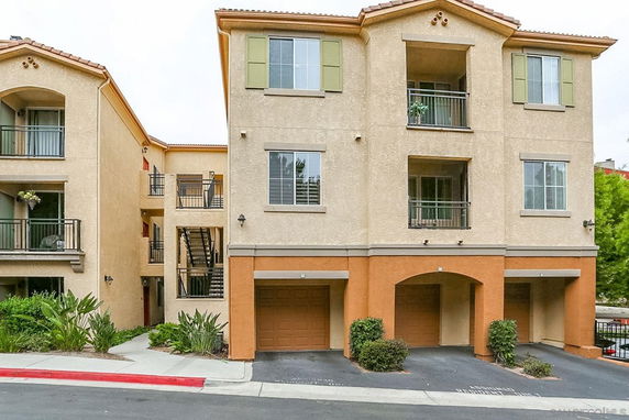 Front view of a multi-story residential building with balconies and garage parking.
