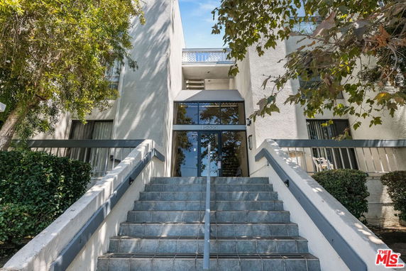 Front view of a multi-story building with stairs leading to the entrance.