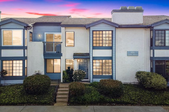 Front view of a two-story townhouse with a small balcony and large windows.