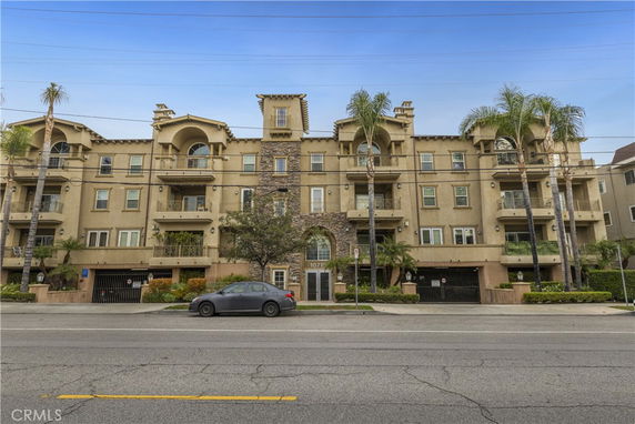 Front view of a multi-story apartment building with balconies and an entrance in the center.