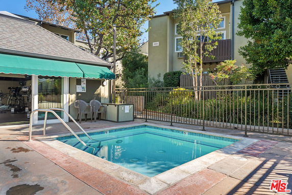View of a swimming pool with a small adjacent building featuring a green awning.