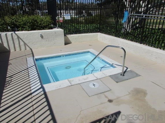 Small outdoor swimming pool with railing and surrounding concrete area.