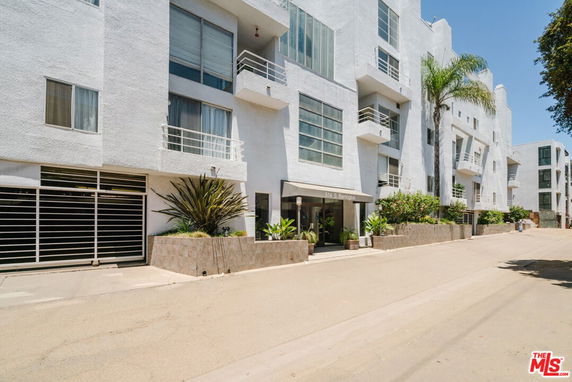 Front view of a modern multi-story apartment building with balconies and large windows.