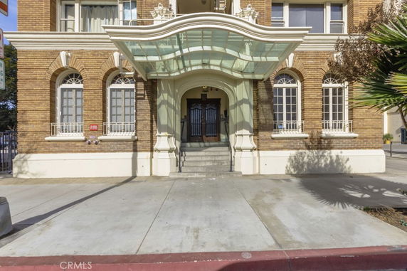 Front view of a multi-story building entrance with arched windows and a glass canopy.
