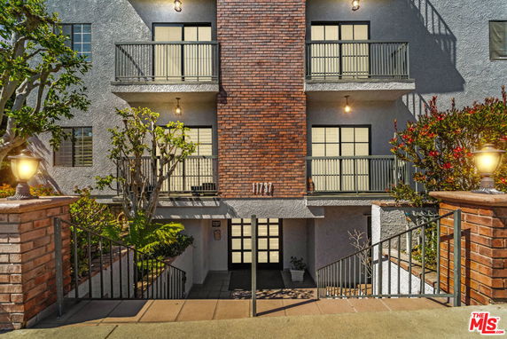 Front view of a multi-story building with brick facade and balconies.