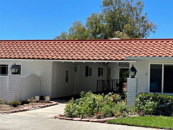Front view of a single-story house with a tile roof and carport.