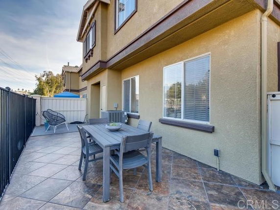 Exterior view of a two-story house with a patio area featuring outdoor furniture.