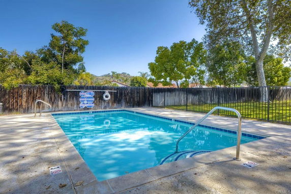 Outdoor swimming pool with surrounding fence and trees.