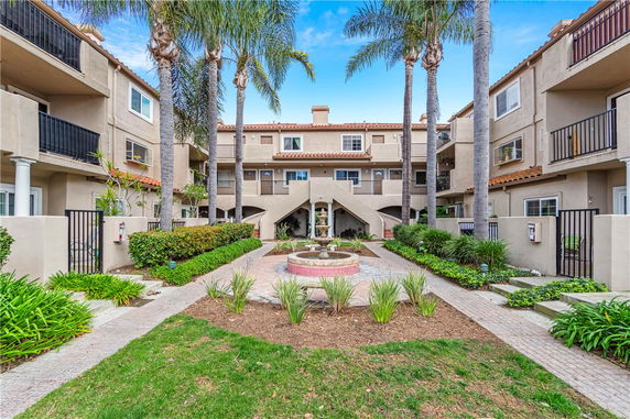 Front view of a multi-story residential building with a central courtyard and water fountain.