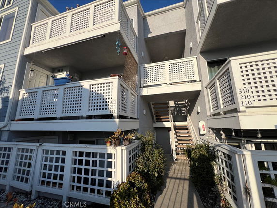 Front view of a multi-story residential building with balconies and outdoor stairs.