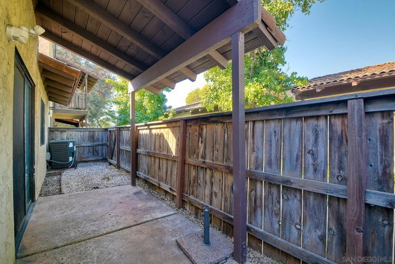 View of a fenced area with a covered patio and an air conditioning unit.
