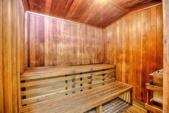 Interior view of a wooden sauna room with benches and a heater.