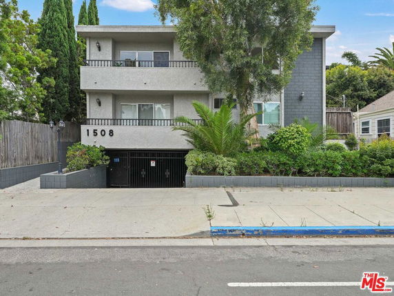Front view of a three-story apartment building with balconies and gated entrance.