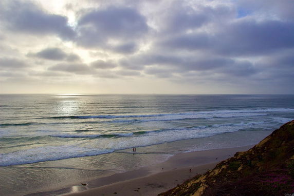 Panoramic view of an ocean with waves and a sandy beach.