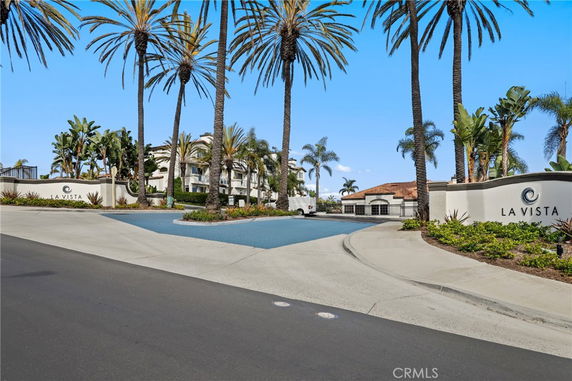 Front view of a residential complex with palm trees and a gated entrance.