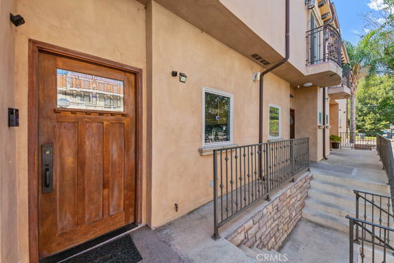 Front view of a multi-story building with balconies and a wooden door entrance.