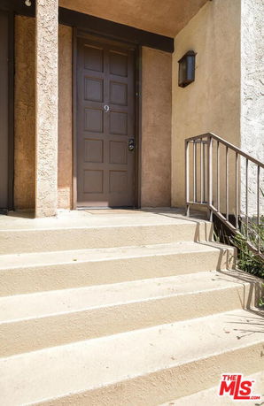 Front steps and door of a house with light-colored walls.