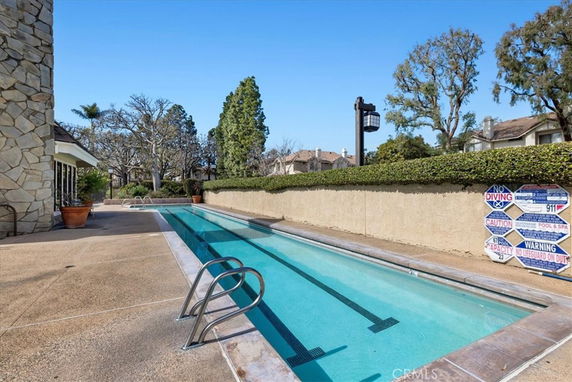Outdoor swimming pool area with a narrow pool alongside a building.