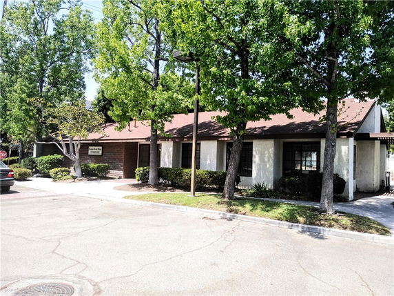Front view of a single-story building with a brown roof and white walls.