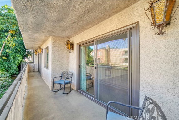 View from a balcony with railing and outdoor chairs, overlooking nearby buildings.