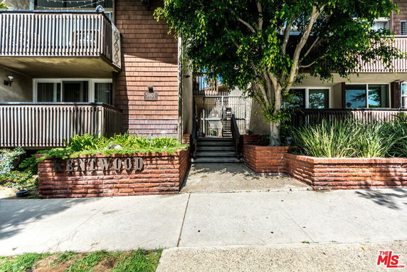 Front view of a residential building with balconies and brick planters.