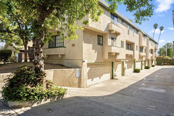 Front view of a multi-story building with multiple garages and beige exterior.