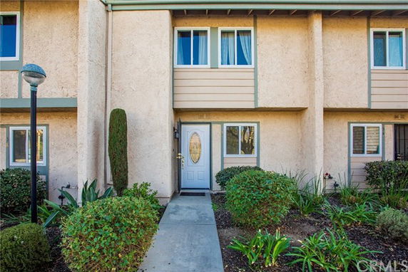 Front view of a two-story townhouse with plants and a walkway leading to the entrance.
