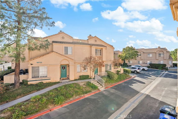 Front view of a two-story house with a green door and a pathway leading to the entrance.