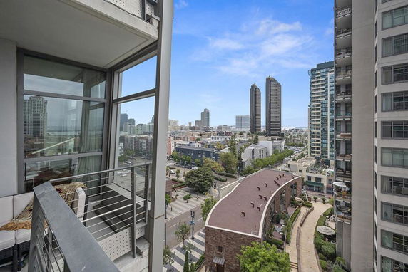 View from a high-rise balcony overlooking a cityscape with multiple tall buildings and streets.