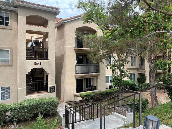Front view of a multi-story apartment building with balconies and external staircases.