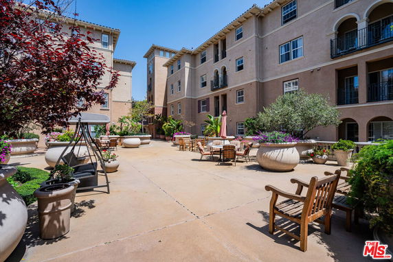 View of a multi-story building with a courtyard featuring outdoor seating and large planters.