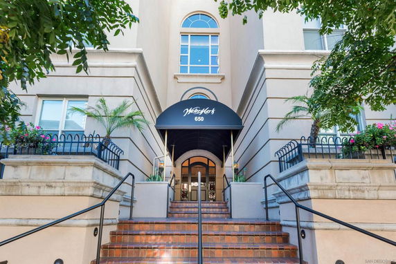 Front view of a multi-story building entrance with a canopy and stairs leading up.