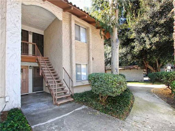 Front view of a two-story building with an external staircase and textured walls.
