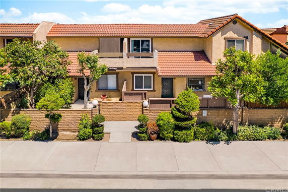 Front view of a two-story house with red tile roof and small balcony.