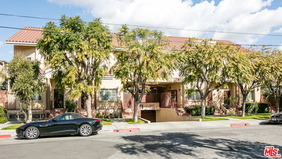 Front view of a multi-story residential building with a tiled roof and entrance.