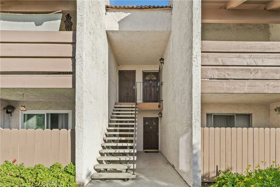 Front view of a multi-story building with exterior staircase and balconies.