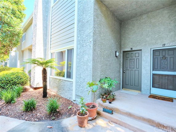 Front view of a residential building with entrance doors and potted plants.