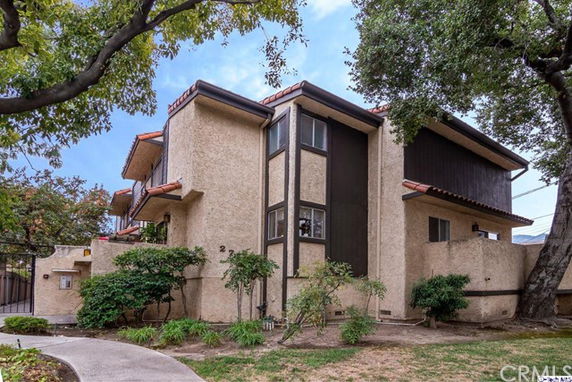 Front view of a two-story residential building with stucco walls and a sloped roof.