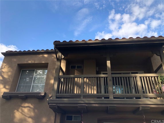 Front view of a house with a balcony and tiled roof.