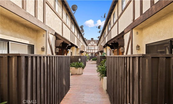 Front view of a two-story residential building with wooden fencing and brick pathway.
