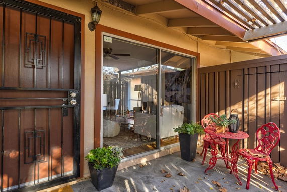 Front view of a house with a sliding glass door, metal security door, and a small outdoor seating area.