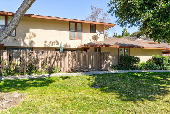 Front view of a two-story house with a wooden fence and patio.