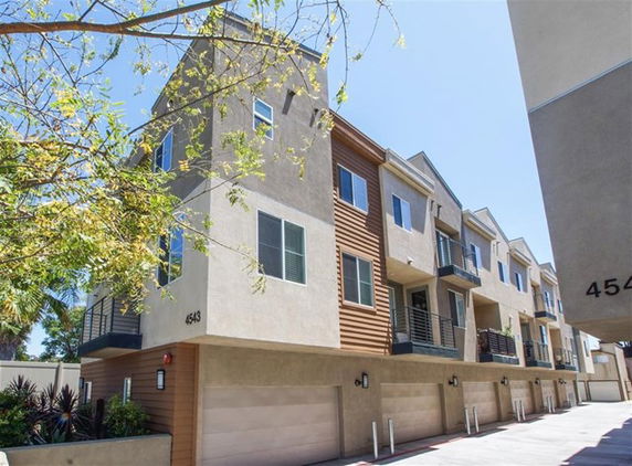Front view of a multi-story residential building with balconies and garages.