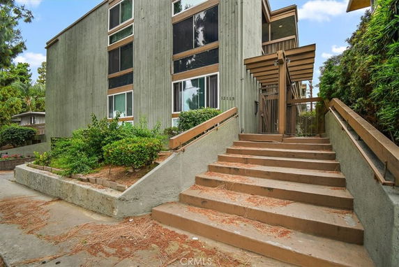Front view of a multi-story building with stairs leading to the entrance.