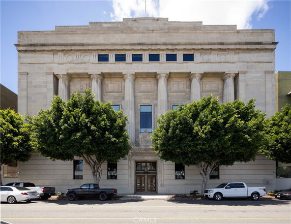 Front view of a large, classical-style stone building with columns and decorative elements.