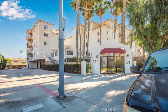 Front view of a multi-story apartment building with gated entrance.