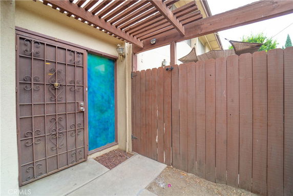 Front view of a house entrance with a metal security door and wooden fence.